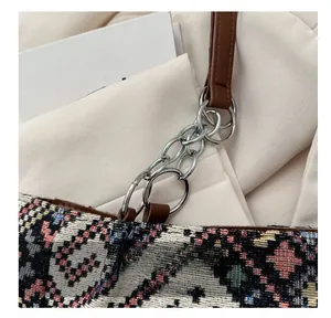 Macro shot of silver metal chain rings joined to a brown leather strap on a woven bag