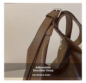 Close-up of adjustable shoulder strap with silver buckle on a dark brown tote bag