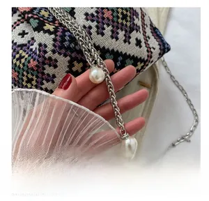Detailed shot of ethnic pattern woven bucket bag with silver chain and large pearl accents