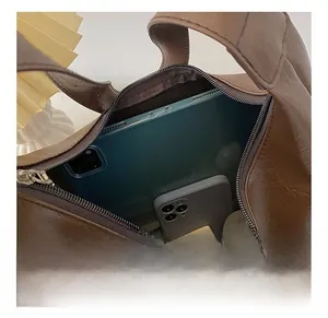 Macro view of the spacious interior of a dark brown crescent tote bag showing daily items