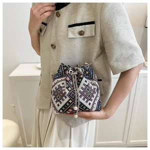 Close-up of geometric woven bucket bag with silver chain strap and pearl drawstrings