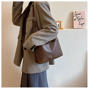 Detail of dark brown leather tote with adjustable shoulder strap and silver metal buckle