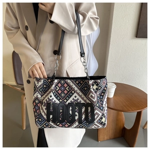 Detail of bohemian canvas tote featuring geometric patterns and leather chain strap