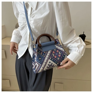Close-up of woven ethnic pattern handbag with round wooden handle and blue leather flap