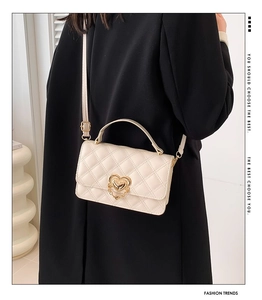 Quilted crossbody bag with heart buckle and metal chain strap on model's back