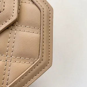 Gros plan sur le cuir beige matelassé et les coutures du sac à bandoulière