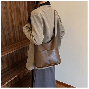 Close-up of deep brown leather hobo bag with decorative stitching on a female model