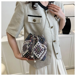 Detailed macro view of ethnic bucket bag featuring geometric patterns and pearl drawstrings