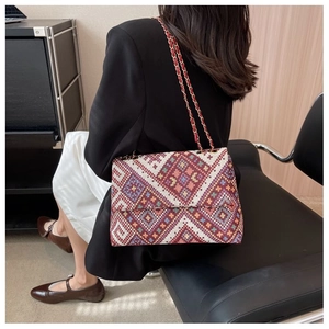 Detailed back view of a woman wearing a colorful ethnic tapestry crossbody bag with chain strap