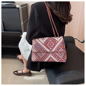 Detail view of ethnic geometric pattern canvas bag with gold chain strap on model