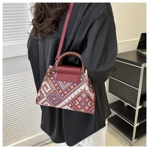 Ethnic pattern canvas handbag shown as crossbody bag on model with wooden handles