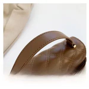 Detailed view of dark brown quilted leather handbag handle with fine stitching