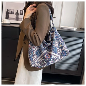 Borsa tote in tela con motivo geometrico etnico e tracolla larga mostrata in un interno