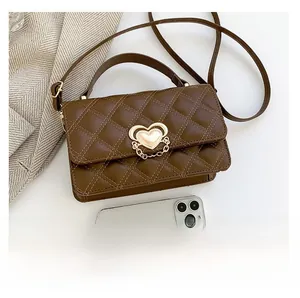Detail of brown quilted bag with gold heart lock and chain on a soft fabric