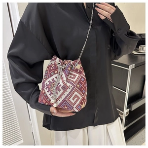 Close-up of ethnic woven bucket bag with geometric patterns and pearl accents