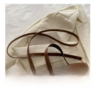 Detail of brown leather bucket bag handle with white contrast stitching and soft texture