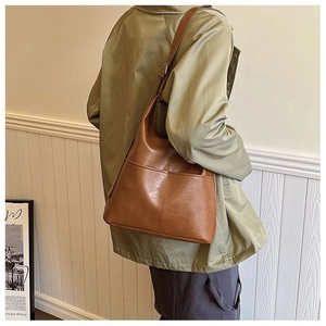 Brown vintage faux leather tote bag with exterior pockets shown on shoulder model