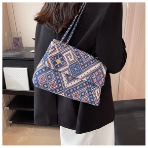 Macro shot of ethnic geometric woven pattern and metallic chain strap on crossbody bag