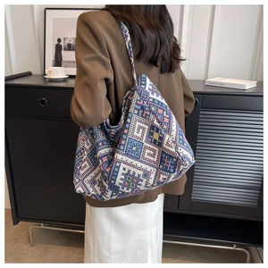 Dettaglio della grande borsa tote etnica intrecciata con motivi geometrici su una modella