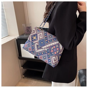 Detail of bohemian geometric woven crossbody bag with vibrant patterns and gold chain