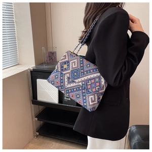 Detail of bohemian woven crossbody bag with geometric patterns and golden chain strap