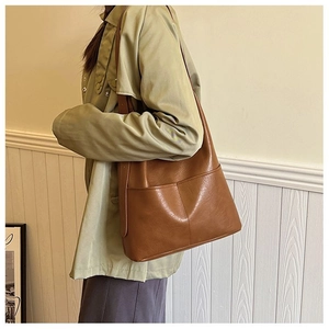 Detail of a brown leather tote bag showing double front pockets and soft texture