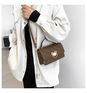 Detailed view of brown quilted crossbody bag with heart-shaped gold clasp and strap