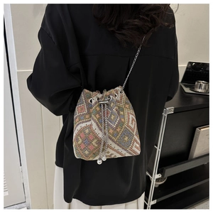Detail of ethnic canvas bucket bag with colorful floral patterns and silver chain strap
