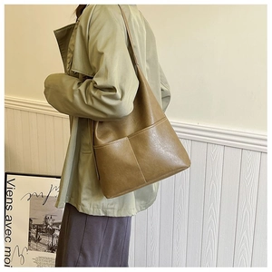 Detail of vintage brown leather tote bag with large front pocket worn by a model