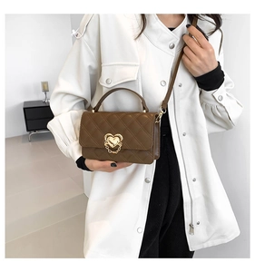 Detail of a dark brown quilted shoulder bag featuring a gold heart buckle and crossbody strap