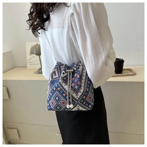 Detail of bohemian geometric bucket bag featuring chain strap and pearl drawstring charms