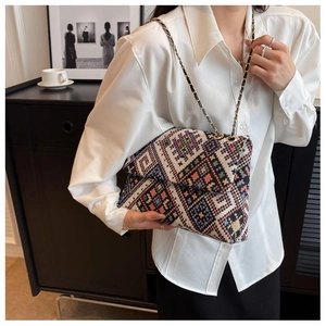 Detail of ethnic woven shoulder bag with colorful geometric patterns and metal chain strap