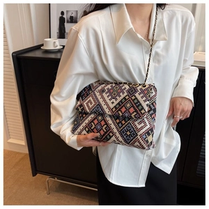 Detail showing the colorful geometric woven pattern and gold chain strap of the crossbody bag