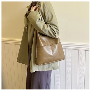 Detail of olive green tote bag with dual front pockets and glossy leather finish