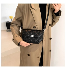 Détail d'un sac bandoulière en cuir noir matelassé avec fermoir rotatif argenté et manteau
