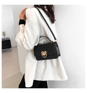 Close-up of black quilted small square bag with golden heart-shaped metal lock and chain detail
