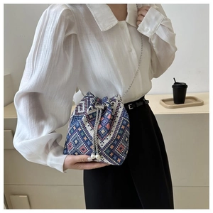 Ethnic style woven bucket bag with silver chain strap and pearl drawstring detail on model