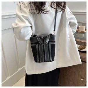Detail of black bucket bag featuring white contrast stitching and premium mixed leather textures