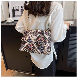 Detailed close-up of colorful ethnic woven texture and gold chain strap on crossbody bag