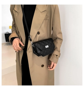 Détail d'un sac bandoulière matelassé noir avec fermoir argenté sur trench-coat