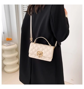 Detailed view of quilted beige crossbody bag featuring a gold heart-shaped metal lock