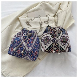 Close-up of ethnic woven bucket bags with silver chain straps and pearl drawstring details