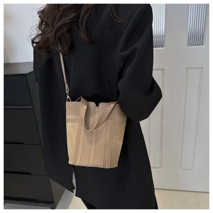 Detail of minimalist beige bucket bag featuring suede and leather texture stitching