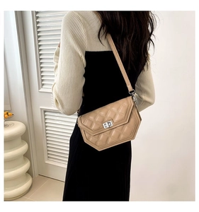 Gros plan sur un sac bandoulière beige matelassé avec fermoir rotatif argenté et losanges
