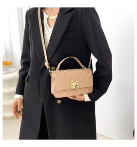 Close-up of quilted beige crossbody bag featuring gold heart lock and chain detail