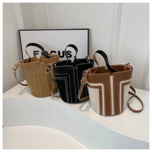 Close-up of leather bucket bags in khaki, black and bicolor with geometric stitching