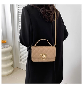 Detail of khaki quilted crossbody bag with heart-shaped gold lock on black blazer