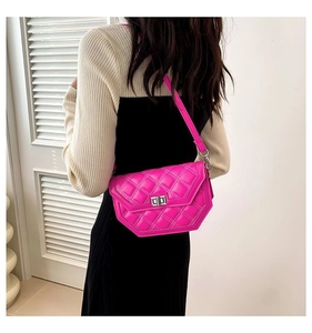 Détail du sac bandoulière matelassé rose avec fermoir rotatif argenté porté par le modèle