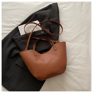 Detail of caramel leather bucket bag with contrast stitching and adjustable strap