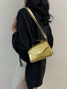 Luxurious gold chain clutch evening bag with fine texture, modeled over the shoulder